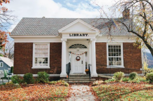 A picture of the Caldwell Lake George Public Library with autumn leaves on the ground.